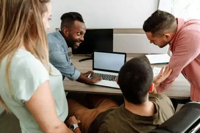 Adultos conversando mientras usan una laptop